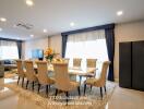 Modern dining room with large table, upholstered chairs, and decorative flowers