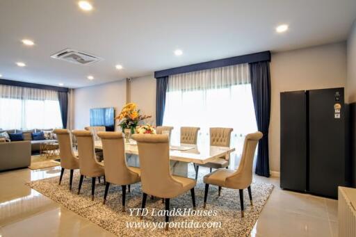 Modern dining room with large table, upholstered chairs, and decorative flowers