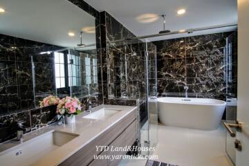 Modern bathroom with marble walls, freestanding bathtub, double sink vanity, and glass-enclosed shower