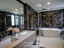 Modern bathroom with marble walls, freestanding bathtub, double sink vanity, and glass-enclosed shower