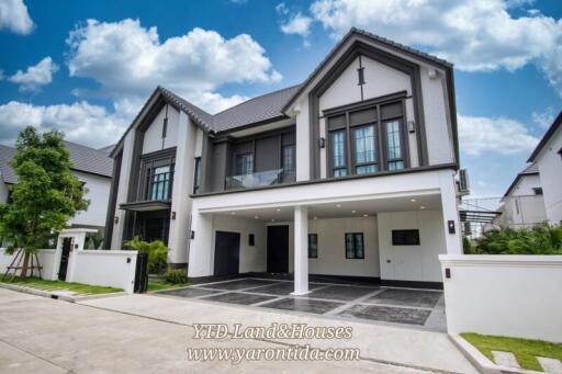 Modern two-story house with spacious driveway and foliage