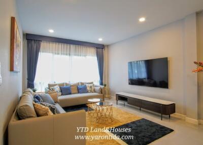 Modern living room with large windows, sofa, coffee table, and wall-mounted TV