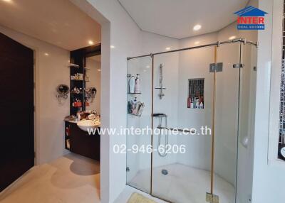 Modern bathroom with a glass shower, sink, and storage area