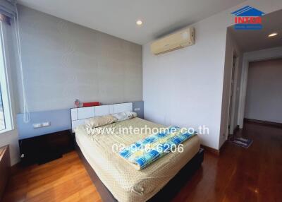 A cozy bedroom with wooden floor, double bed, and air conditioning