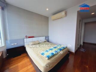 A cozy bedroom with wooden floor, double bed, and air conditioning