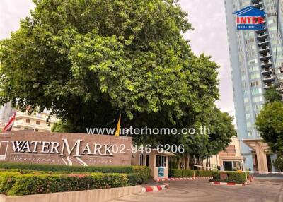 Entrance to WaterMark Residences with signage and surrounding greenery