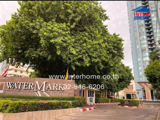 Entrance to WaterMark Residences with signage and surrounding greenery