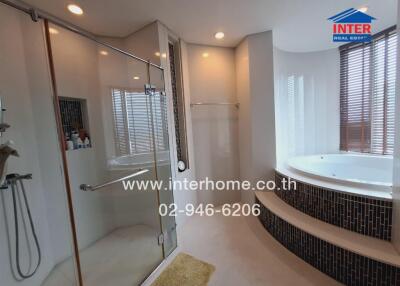 Luxurious bathroom with glass shower and large bathtub.