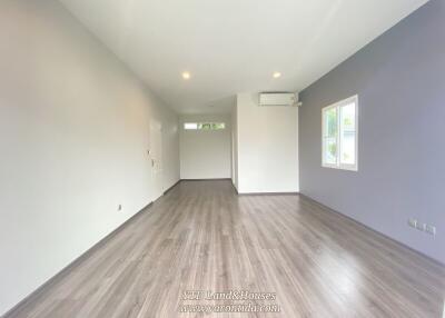 Spacious living area with large window and wooden flooring