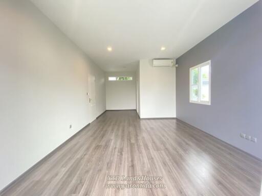 Spacious living area with large window and wooden flooring