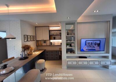 Modern living area with built-in TV unit, workspace, and dining corner