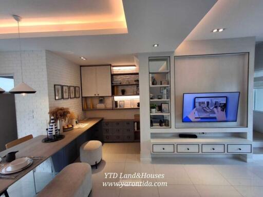 Modern living area with built-in TV unit, workspace, and dining corner