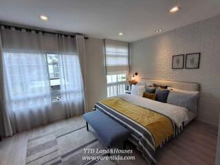 Modern bedroom with double bed, large windows, and decorative accents