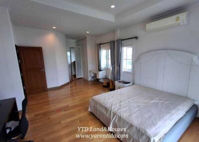 Spacious bedroom with wooden flooring, large windows, and a double bed