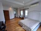 Spacious bedroom with wooden flooring, large windows, and a double bed