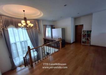 Well-lit living area with chandelier and wooden flooring