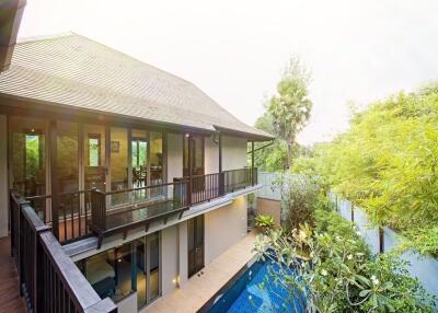 Exterior view of a two-story house with a balcony and pool area