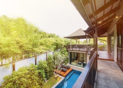 Exterior view of a house with a balcony overlooking a pool and garden