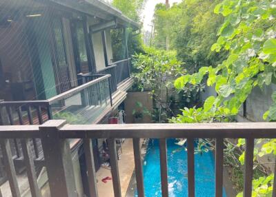 View from the balcony overlooking a swimming pool and lush greenery