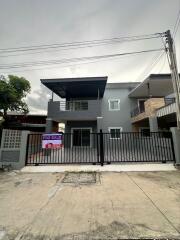 Exterior view of a two-story house with a for sale sign