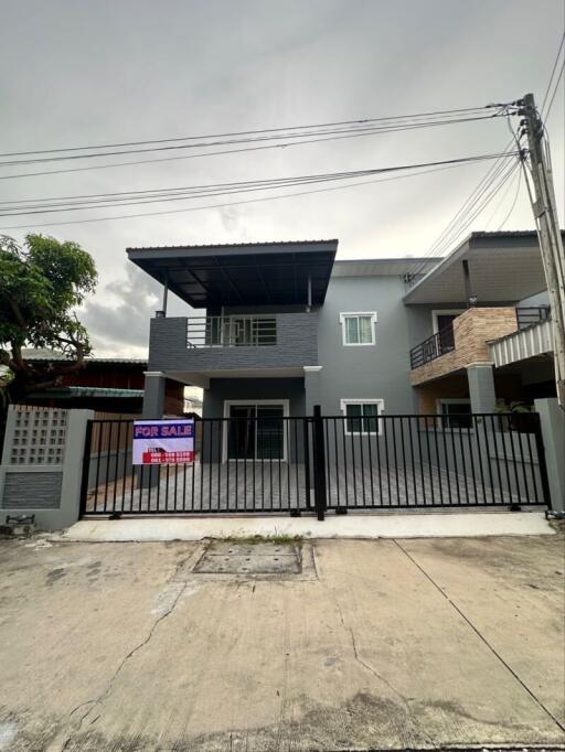 Exterior view of a two-story house with a for sale sign