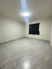 Empty bedroom with tile flooring and a window with black curtains