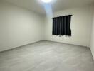 Empty bedroom with tile flooring and a window with black curtains