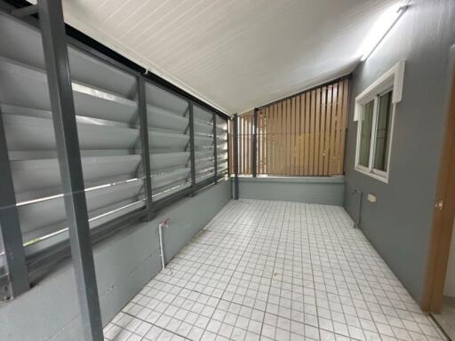 Enclosed patio with tiled flooring and louvered windows