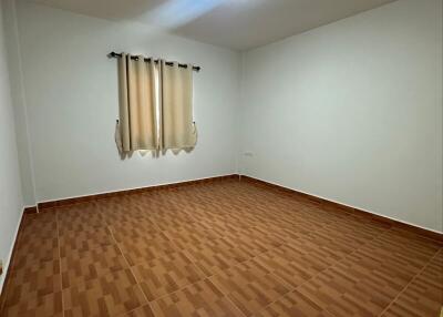 Empty bedroom with tiled floor and window with curtains