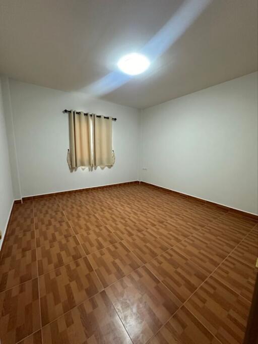 Empty bedroom with tiled floor and window with curtains