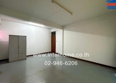 Empty room with gray flooring and white walls, with a cabinet, door, and fluorescent light