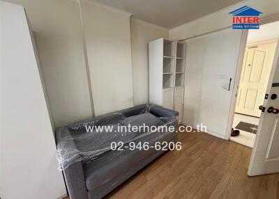 Small living room with a grey couch, white cabinets, and wooden flooring