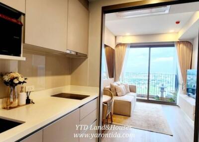 Modern kitchen area leading to a bright living room with large windows