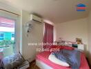 Bedroom with pink bed, wall-mounted air conditioner, and a window with a view