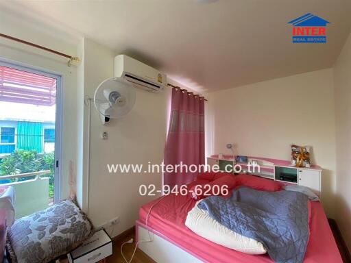 Bedroom with pink bed, wall-mounted air conditioner, and a window with a view