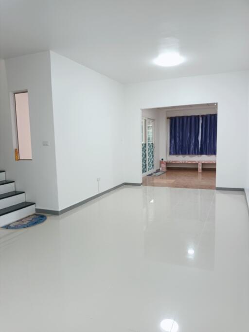 Spacious living room with white walls and glossy floor tiles