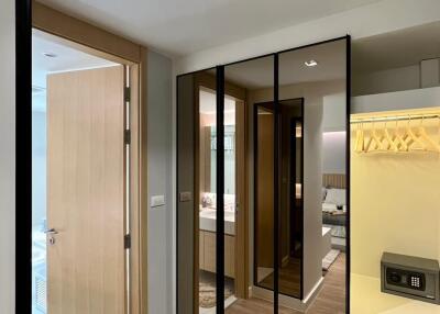 Modern bedroom interior with wooden flooring, mirrored closet doors, ceiling light, and a view of an ensuite bathroom