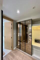 Modern bedroom interior with wooden flooring, mirrored closet doors, ceiling light, and a view of an ensuite bathroom