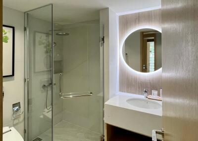 Modern bathroom with glass shower, illuminated mirror, and sink