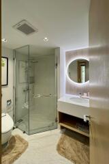 Modern bathroom with glass shower, illuminated mirror, and sink