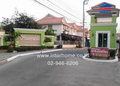 Residential gated community entrance with security booth and houses in the background