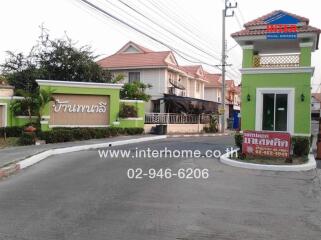 Residential gated community entrance with security booth and houses in the background