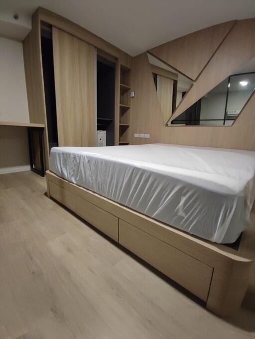 Modern bedroom with wooden flooring, bed frame, and built-in wardrobe