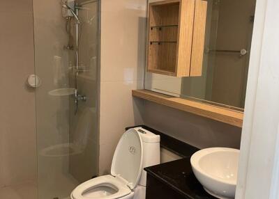 Modern bathroom with glass shower, toilet, and sink