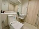 Modern bathroom with a toilet, sink, and large mirror