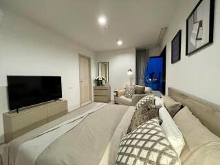 Modern bedroom with large bed, TV, and city view