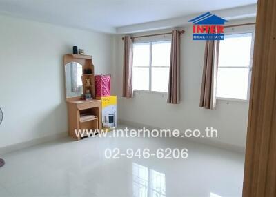 Spacious bedroom with two windows, a vanity desk, and a fan