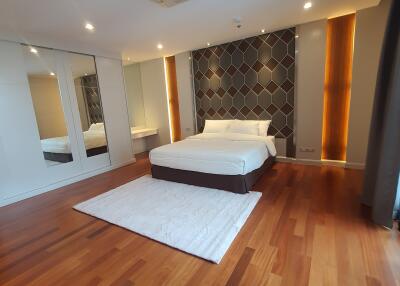 Spacious modern bedroom with hardwood floors and accent wall