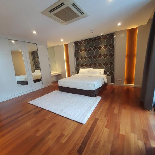 Spacious modern bedroom with hardwood floors and accent wall