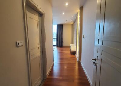 Hallway with wooden floor and closed doors leading to living areas